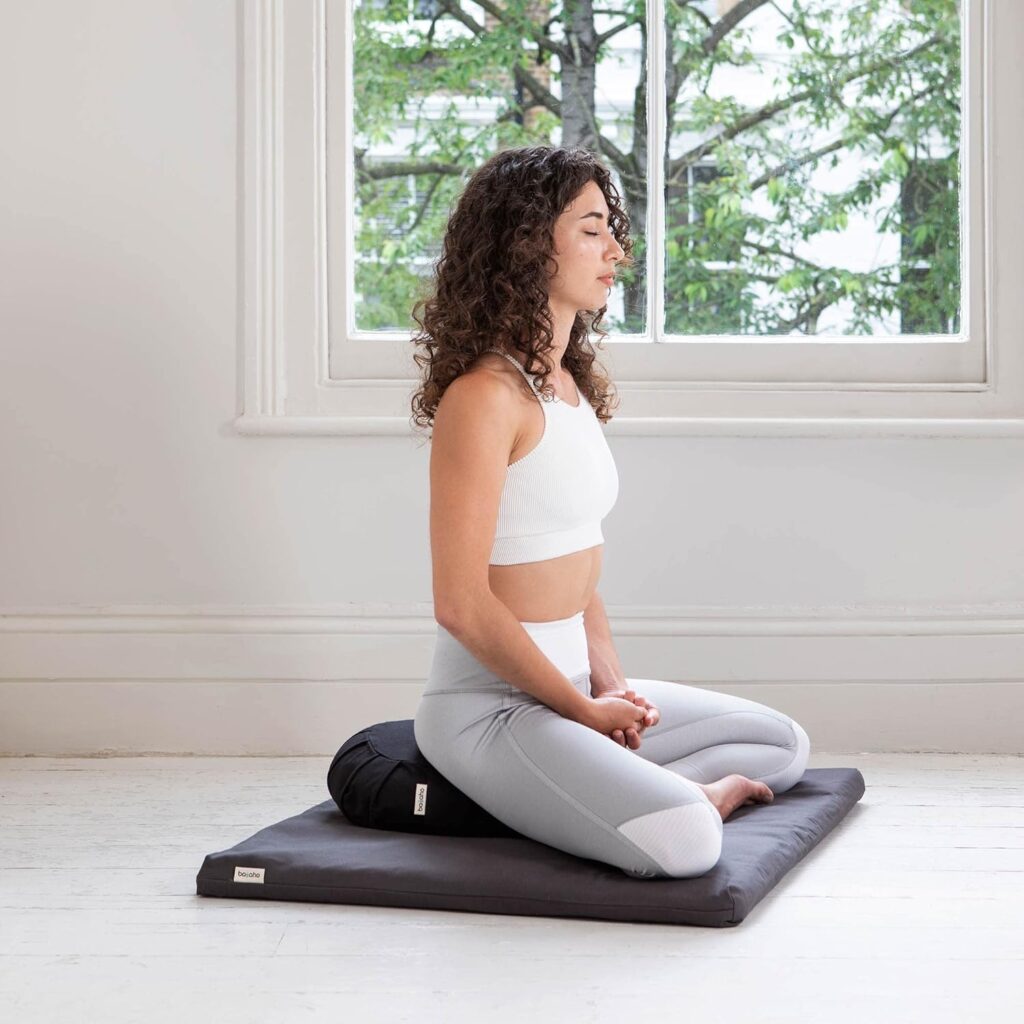 Persona sentada en postura de meditación sobre la Esterilla de Meditación Basaho Zabuton.